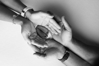 Ebeveynlerin avuç içleri, anne ve babanın bacakları, yeni doğmuş bir bebeğin ayakları. Yeni doğmuş bir çocuğun ayakları, topukları ve ayak parmakları yakın plan. Profesyonel makro fotoğraf. Siyah ve beyaz. Yüksek kalite fotoğraf