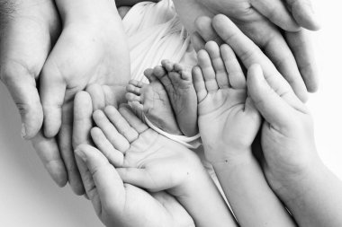 Baba 'nın avuç içi, anne yeni doğan bebeğin ayağını tutuyor. Yeni doğan bebeğin ayakları, ebeveynlerin avuçlarında. Stüdyo makro siyah beyaz bir çocuk fotoğrafı. Parmak, topuklar ve ayaklar.. 