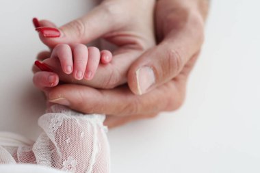 Close-up little hand of child and palm of mother and father. The newborn baby has a firm grip on the parents finger after birth. A newborn holds on to moms, dads finger. 