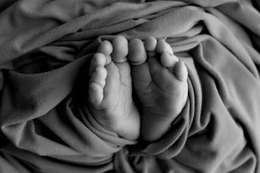 Yeni doğmuş bir bebeğin ayağı. Ayaklarını, ayak parmaklarını, topuklarını, yeni doğmuş bir bebeğin ayaklarını kapat. Stüdyo monokromu, vintage tarzı, siyah beyaz makro fotoğraf. 