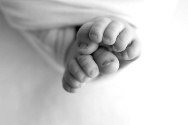 Yeni doğmuş bir bebeğin ayağı. Ayaklarını, ayak parmaklarını, topuklarını, yeni doğmuş bir bebeğin ayaklarını kapat. Stüdyo monokromu, vintage tarzı, siyah beyaz makro fotoğraf. 