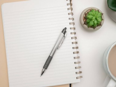 Pot with Plant and Cup Standing on Desk. Iinfrormation written on paper.