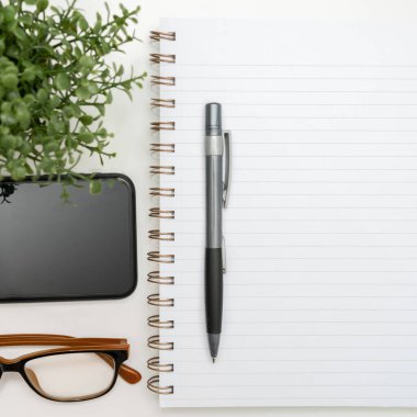 Notebook With Important Messages On Desk With Coffee, Phone And Pen.