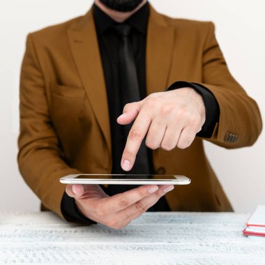 Businessman in a Brown jacket sitting at a table holding a mobile phone