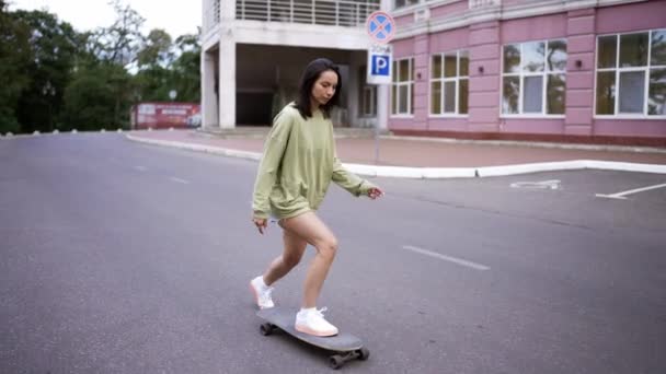 一个年轻的黑发女孩跑上来 熟练地骑在滑板上保持平衡 业余爱好 — 图库视频影像