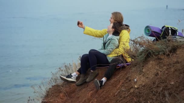 一对旅行的夫妇坐在悬崖顶上 用智能手机摆出一副自拍的样子 — 图库视频影像