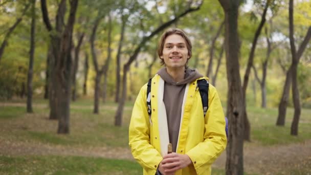 Χαρούμενος Νεαρός Άνδρας Κίτρινο Παλτό Σακίδιο Στέκεται Και Χαμογελά Στο — Αρχείο Βίντεο