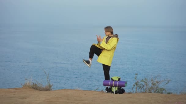 Νεαρός Ταξιδιώτης Στέκεται Στην Άκρη Του Λόφου Μπροστά Στη Θάλασσα — Αρχείο Βίντεο