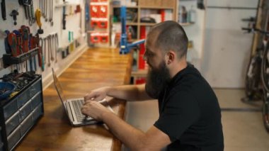 Kafkas ustası bisiklet atölyesinde dizüstü bilgisayar kullanıyor..