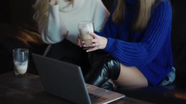 Beautiful girls are talking over a cup of cappuccino at the cafe.