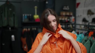Young woman trying at sport jacket in clothing store.