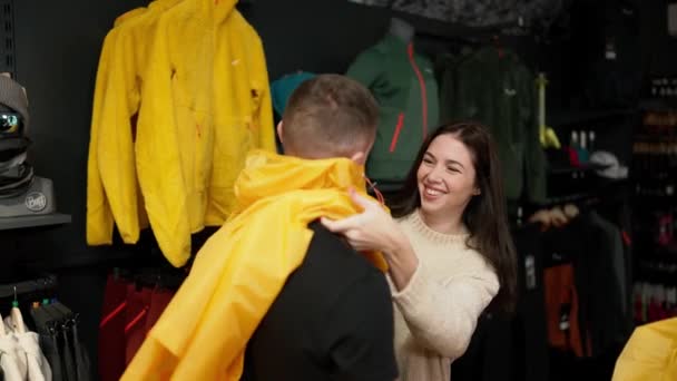 Woman Trying Her Man Rain Jacket Clothing Store Making Fun — Stockvideo