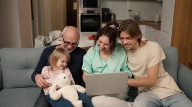 Children and grandpa are smiling while using a laptop.