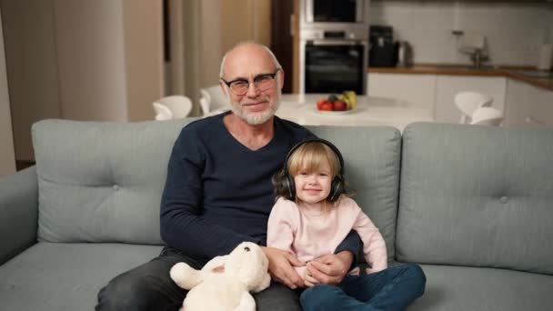 Portrait Small Girl Headphones Her Grandpa While Sitting Sofa — Stock video