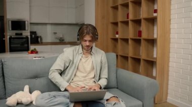 Young man in headphones make video call using laptop sitting at home.