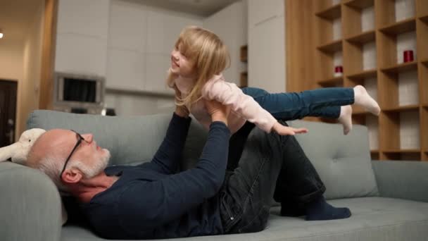 Granddaughter Playing Her Grandfather Sofa Pretending Fly — Vídeo de Stock