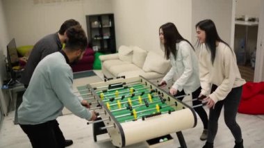 Coworkers enjoying soccer game at foosball table after work.