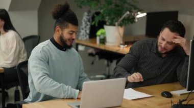 Two male colleagues employees cooperating in office, shaking hands with common result.