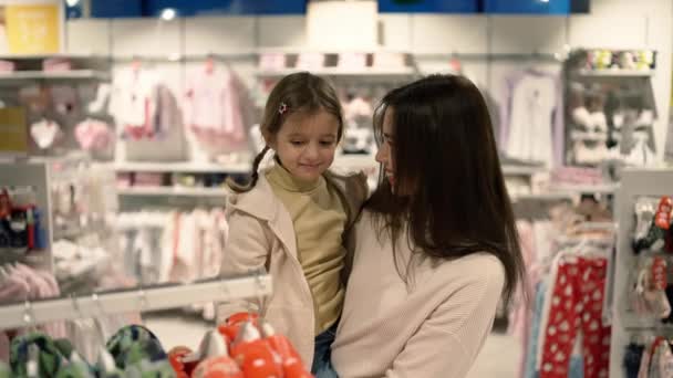 Schöne Mutter Sucht Kleidung Auf Kleiderbügel Mit Tochter Einkaufszentrum — Stockvideo