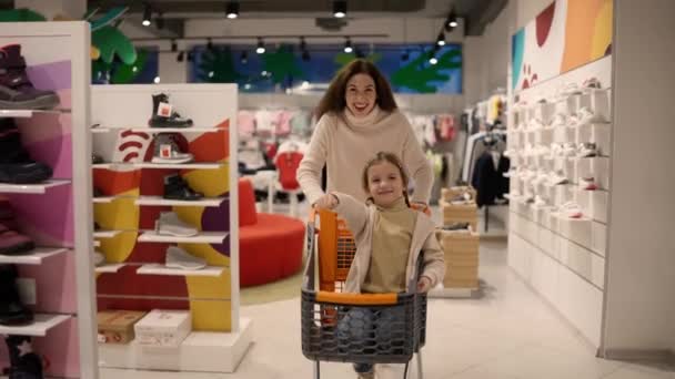 母亲和孩子的滑稽动作乘坐购物车去现代贸易或购物中心 — 图库视频影像
