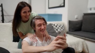 Happy couple, video call and phone with smile on bed in the bedroom relax at home in happiness.