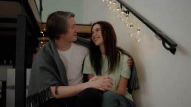 Young couple relaxing on wooden stairs, embracing each other.