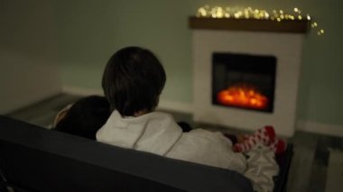 Couple sitting at home by the fireplace embraced.