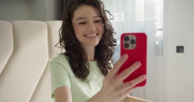 Esmer kadın evde akıllı telefonuyla görüntülü arama yapıyor..