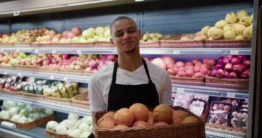 Önlüklü genç adam elinde portakallarla kameraya poz veriyor..