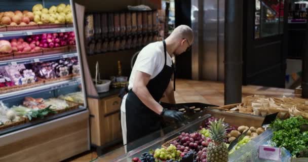 黒エプロンの男労働者と手袋スーパーマーケットで果物をストック — ストック動画