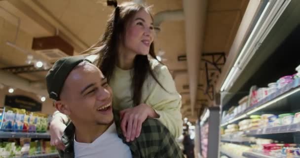 年轻有趣的男朋友背着女朋友 在超市里挑选商品 — 图库视频影像