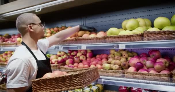 黒エプロンの労働者がスーパーマーケットで新鮮な柑橘類をアレンジ — ストック動画