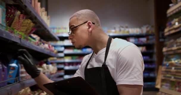 Önlüklü Karışık Yarış Işçisi Raftaki Süpermarkette Tablet Kullanarak Malları Sayıyor — Stok video