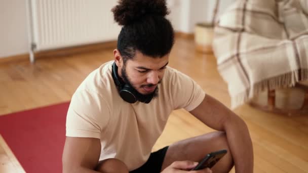 Sportsman Siedzi Macie Fitness Telefonem Komórkowym Słuchając Muzyki Słuchawkami Bezprzewodowymi — Wideo stockowe