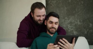 Neşeli beyaz adamlar dijital tablette video izleyip, ekranı gösterip gülümsüyor..