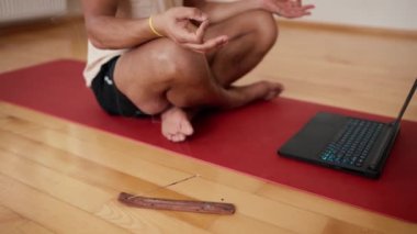 Parmaklarını birleştirir ve aroma çubuğuyla dizüstü bilgisayarda meditasyon yapar..