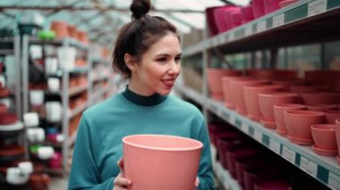 Genç bayan müşteri çiçekçide dolaşmak için kilden saksıyı seçmiş..