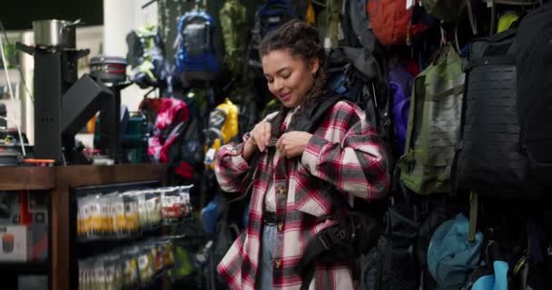 年轻女子在体育用品店里试用大旅行袋 — 图库视频影像