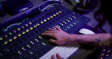 Omuz üstünden çekim: ses üreticisi el kayıt stüdyosunda düzenleme araçları ile bir müzik karıştırıcı kullanıyor.