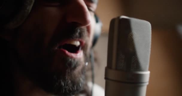 一个满脸胡须的男人正在唱着新歌 带着激情和口水对着话筒唱歌 — 图库视频影像