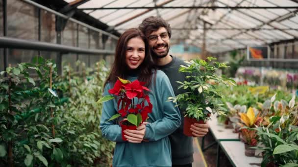 年轻貌美 穿着休闲装 两人持着植物 看着相机 面带微笑 — 图库视频影像