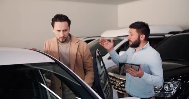 男性经销商在向男性展示新型豪华轿车时使用数码平板电脑 — 图库视频影像