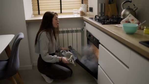 長い髪の女性オープン煙充填オーブンでキッチン — ストック動画