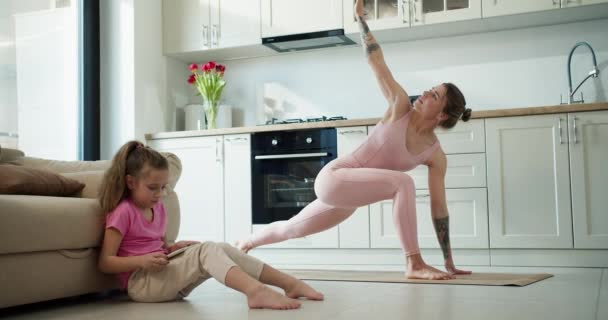 漂亮的女人在厨房做瑜伽 而她的孩子在地板上玩耍 — 图库视频影像