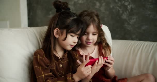 Dwoje Uśmiechniętych Dzieci Siedzi Kanapie Patrzy Ekran Telefonu Bawi Się — Wideo stockowe
