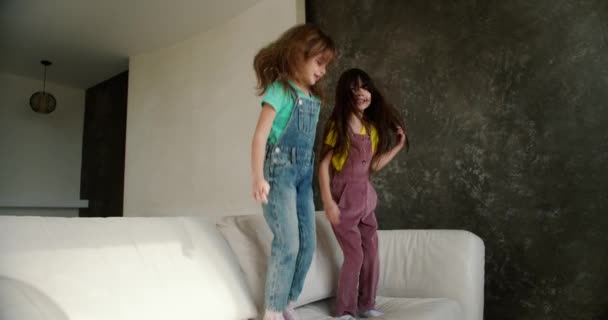 Dos Niñas Hermanas Divierten Saltando Sofá Blanco — Vídeo de stock