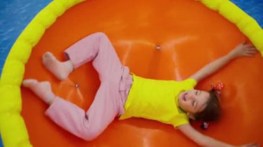 Kapalı alandaki oyun merkezinde renkli dönen tabakta heyecanlı bir kız..