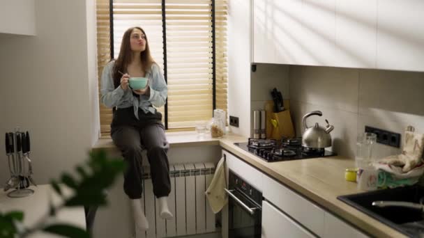 Młoda Beztroska Kobieta Płatki Śniadaniowe Siedząc Parapecie Domu Kuchnia Zwolniony — Wideo stockowe
