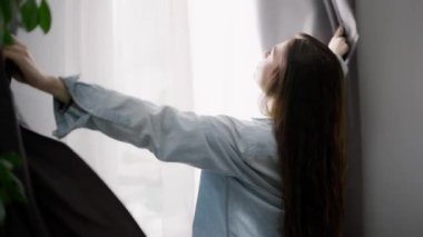 Uzun saçlı kadın sabah pencerenin perdelerini açar..