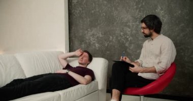 Memnuniyetsiz bir adam terapi seansında danışman ile konuları hakkında konuşuyor, kanepede yatıyor..